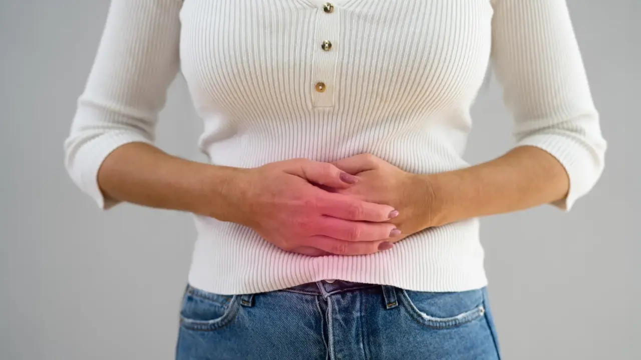 Kvinna håller sig om magen med en röd glöd som indikerar smärta, möjligen relaterat till pelvic congestion syndrome svenska.