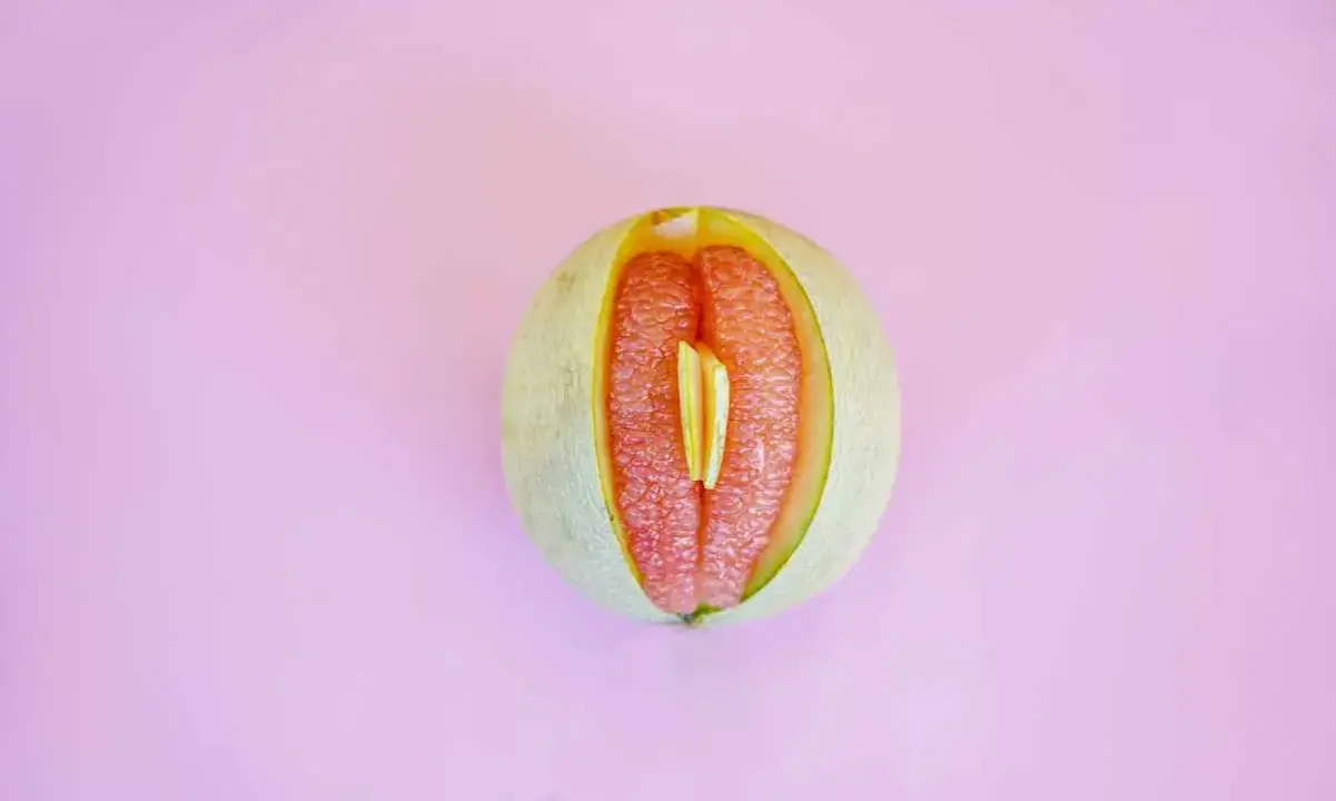 En melon delad på mitten, med en bit av en annan frukt inuti. Kan liknas vid ett svullet underliv, kanske som en graviditet kan kännas.