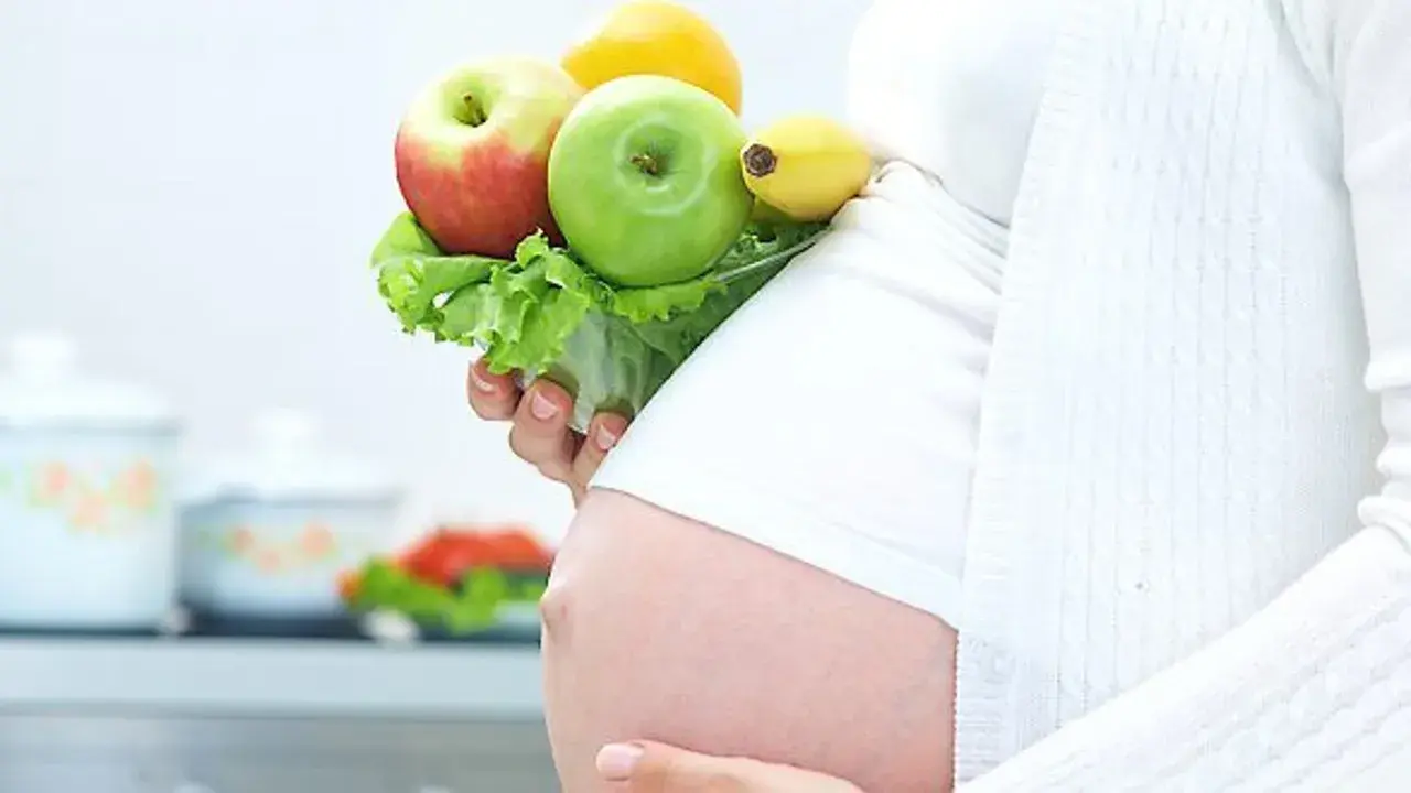 Gravid kvinna med LCHF-vänlig frukt och grönsaker i handen. En hälsosam kost för en LCHF graviditet.