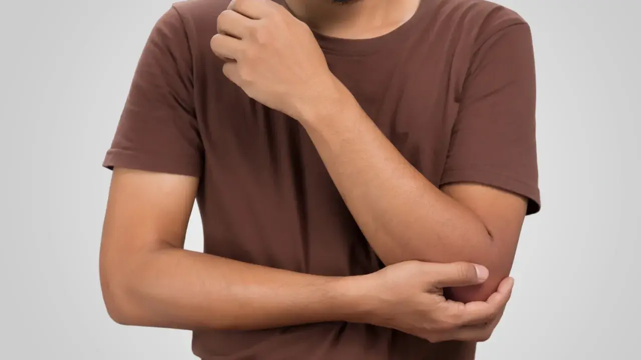 Man håller om sin armbåge, där den mediala epikondylen kan kännas öm.