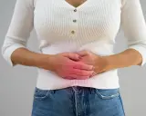 Kvinna håller sig om magen med en röd glöd som indikerar smärta, möjligen relaterat till pelvic congestion syndrome svenska.