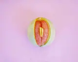 En melon delad på mitten, med en bit av en annan frukt inuti. Kan liknas vid ett svullet underliv, kanske som en graviditet kan kännas.