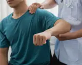 Läkare undersöker en patients arm, möjligen för att diagnostisera spricka i armbågen symtom.