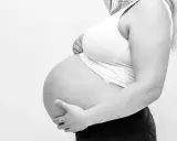 Gravid mage med händer som stöttar. Kanske ont i ljumsken gravid?