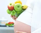 Gravid kvinna med LCHF-vänlig frukt och grönsaker i handen. En hälsosam kost för en LCHF graviditet.