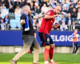 En åskådare ger en fotbollsspelare ett hårt slag mot hakan på planen.