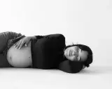 Gravid kvinna ligger på rygg, med handen på sin mage. Hon ser ut att vila.