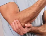 En person håller om sin armbåge, som om den har ont i armbågen.