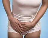 Kvinna håller handen över magen, upplever tidigt gravid ont i sidan av magen.