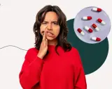 Kvinna med tandvärk håller handen mot kinden, bredvid en skål med kapslar som kan symbolisera tandinfektion och antibiotika.