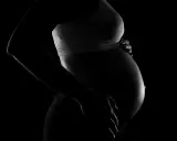 Silhuett av en gravid kvinna som håller sin mage. En bakåtlutad livmoder är tydligt synlig under den sträckta huden.