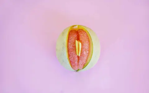 En melon delad på mitten, med en bit av en annan frukt inuti. Kan liknas vid ett svullet underliv, kanske som en graviditet kan kännas.