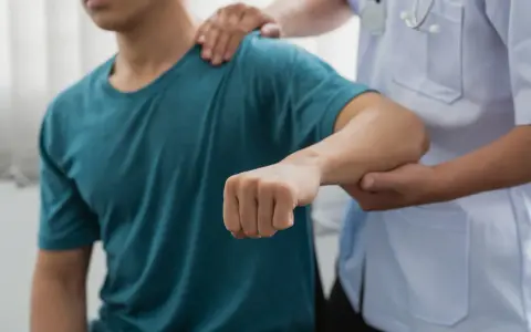 Läkare undersöker en patients arm, möjligen för att diagnostisera spricka i armbågen symtom.