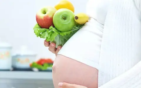 Gravid kvinna med LCHF-vänlig frukt och grönsaker i handen. En hälsosam kost för en LCHF graviditet.