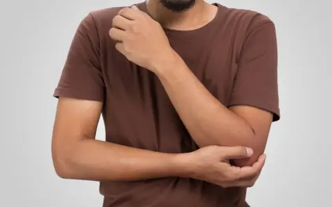 Man håller om sin armbåge, där den mediala epikondylen kan kännas öm.