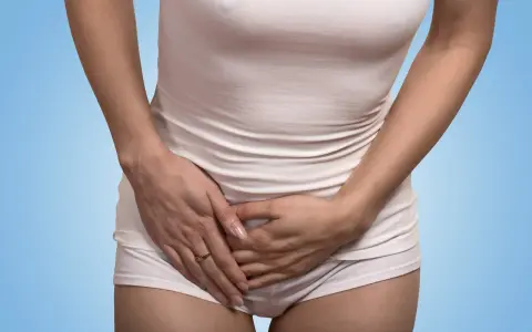 Kvinna håller handen över magen, upplever tidigt gravid ont i sidan av magen.