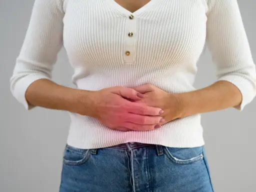 Kvinna håller sig om magen med en röd glöd som indikerar smärta, möjligen relaterat till pelvic congestion syndrome svenska.
