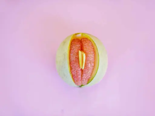 En melon delad på mitten, med en bit av en annan frukt inuti. Kan liknas vid ett svullet underliv, kanske som en graviditet kan kännas.