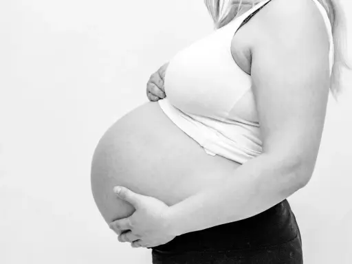 Gravid mage med händer som stöttar. Kanske ont i ljumsken gravid?