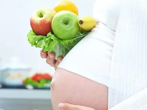 Gravid kvinna med LCHF-vänlig frukt och grönsaker i handen. En hälsosam kost för en LCHF graviditet.