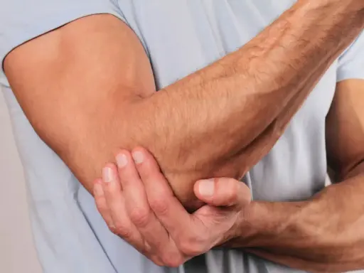 En person håller om sin armbåge, som om den har ont i armbågen.