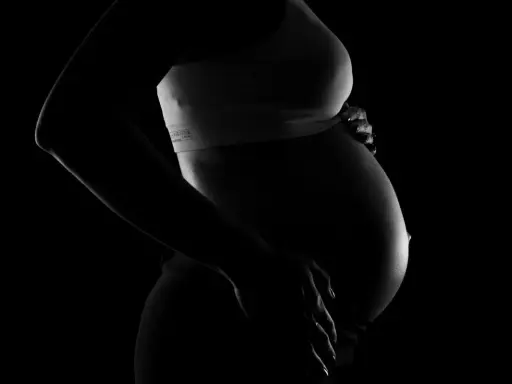 Silhuett av en gravid kvinna som håller sin mage. En bakåtlutad livmoder är tydligt synlig under den sträckta huden.