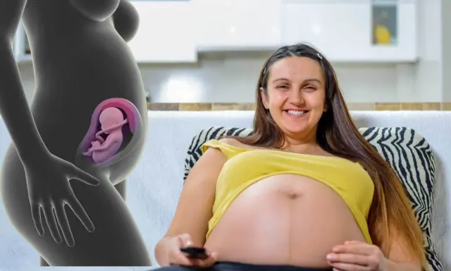 En gravid kvinna ler och håller i fjärrkontrollen. Till vänster syns en illustration av en livmoder med en bebis position i magen.