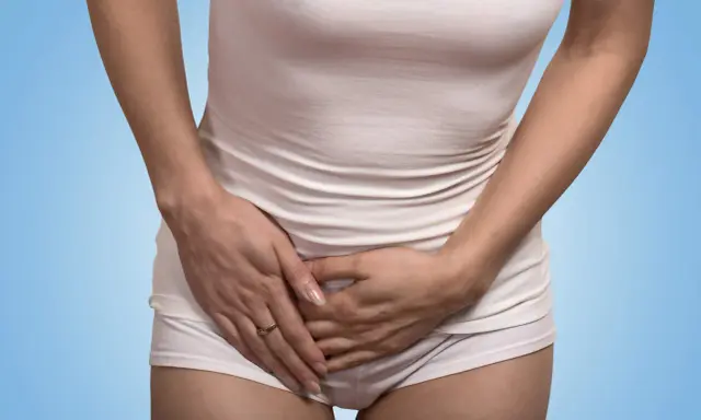 Kvinna håller handen över magen, upplever tidigt gravid ont i sidan av magen.