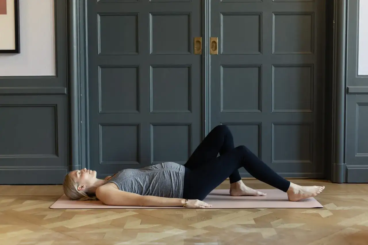 Kvinna p&aring; yogamatta med b&ouml;jda kn&auml;n, &ouml;vning f&ouml;r foglossning blygdbenet.